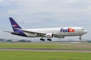 FedEx cargo airplane on the runway during takeoff at a busy airport.